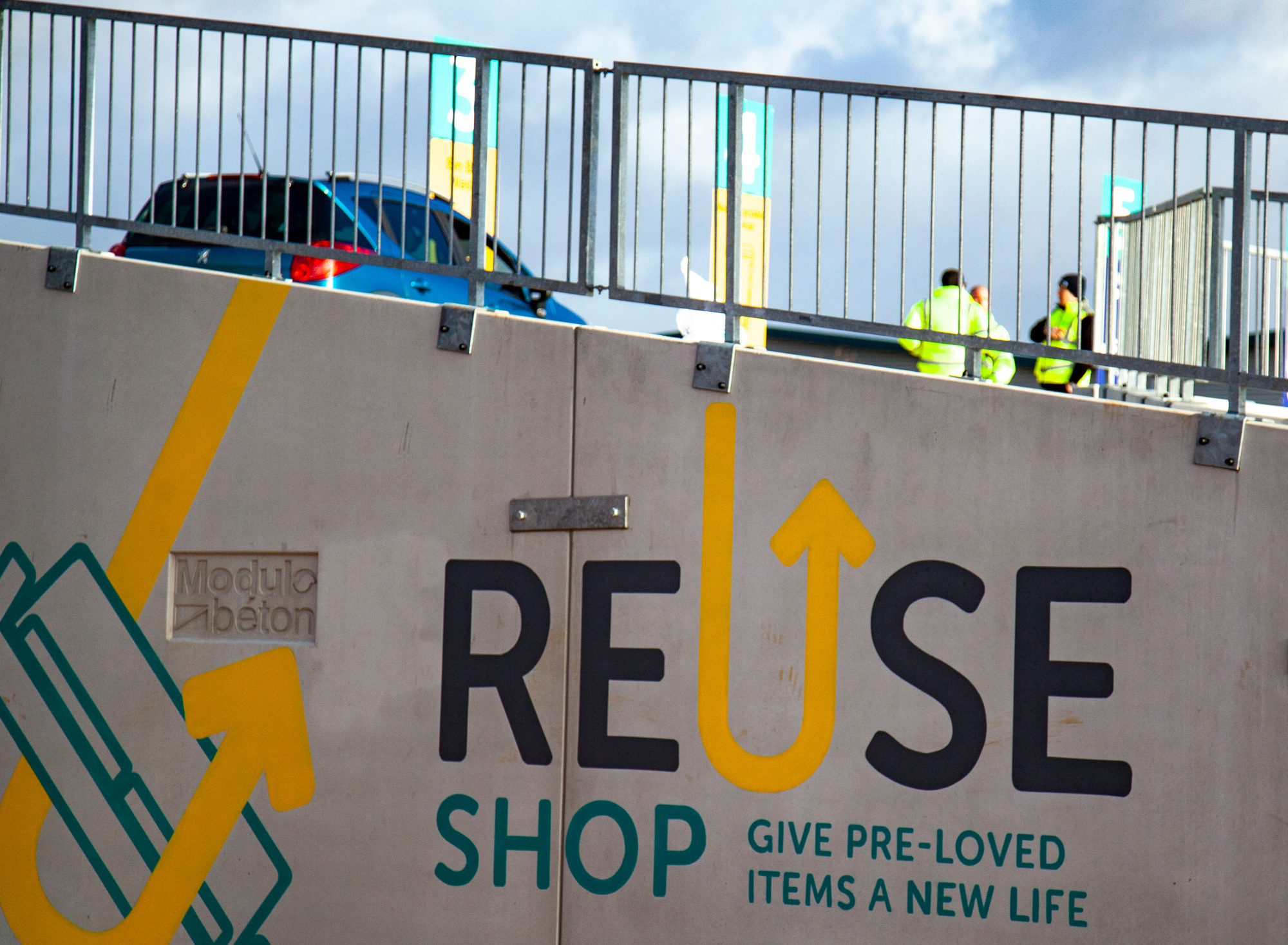 Photo: Sign painted on side of concrete barriers saying "Reuse Shop Give pre-loved items a new life"