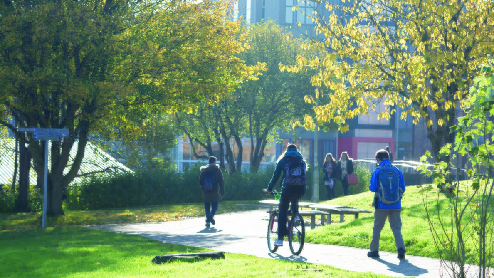 Image of UWE's Frenchay Campus with two walkers and a cyclist amongst trees