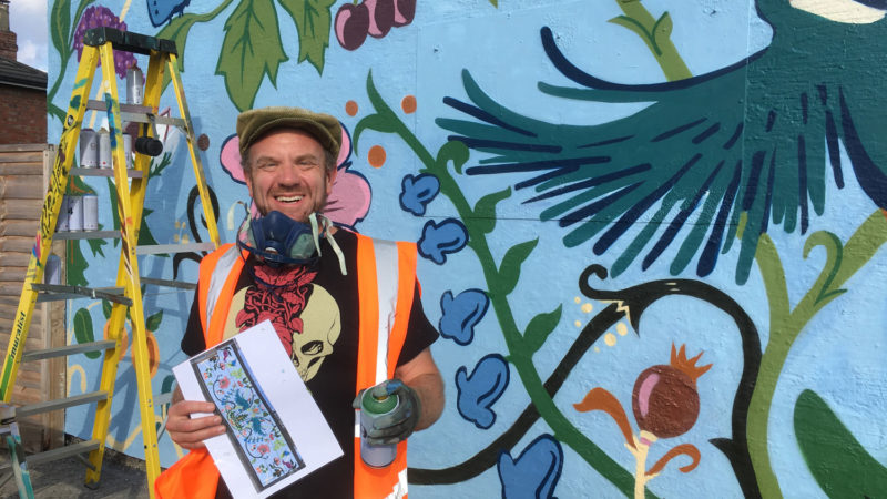 Rob Wheeler stands in front of a mural