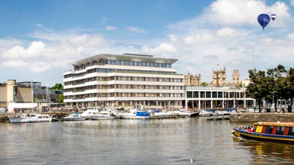 CGI of large, modern building on Bristol's harbourside, overlooking the water where boats rest in front. Hot air balloons in the sky overhead