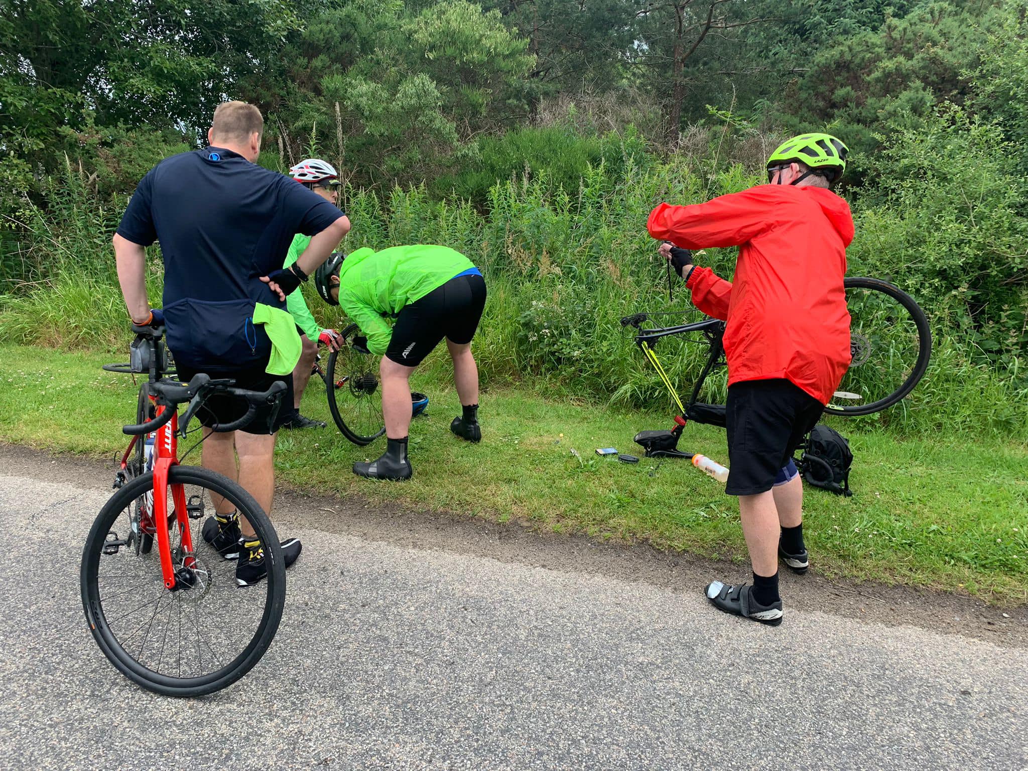 4 men stand around an upside down bike, they are changing the tyre