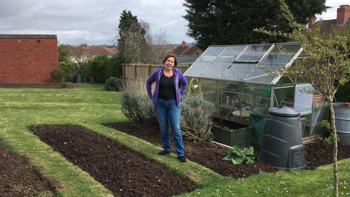 Women standing on her allotment, next to a greenhouse at Sea Mills