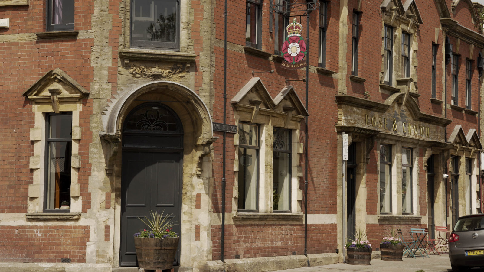The outside of a red brick pub, with a sign which says 