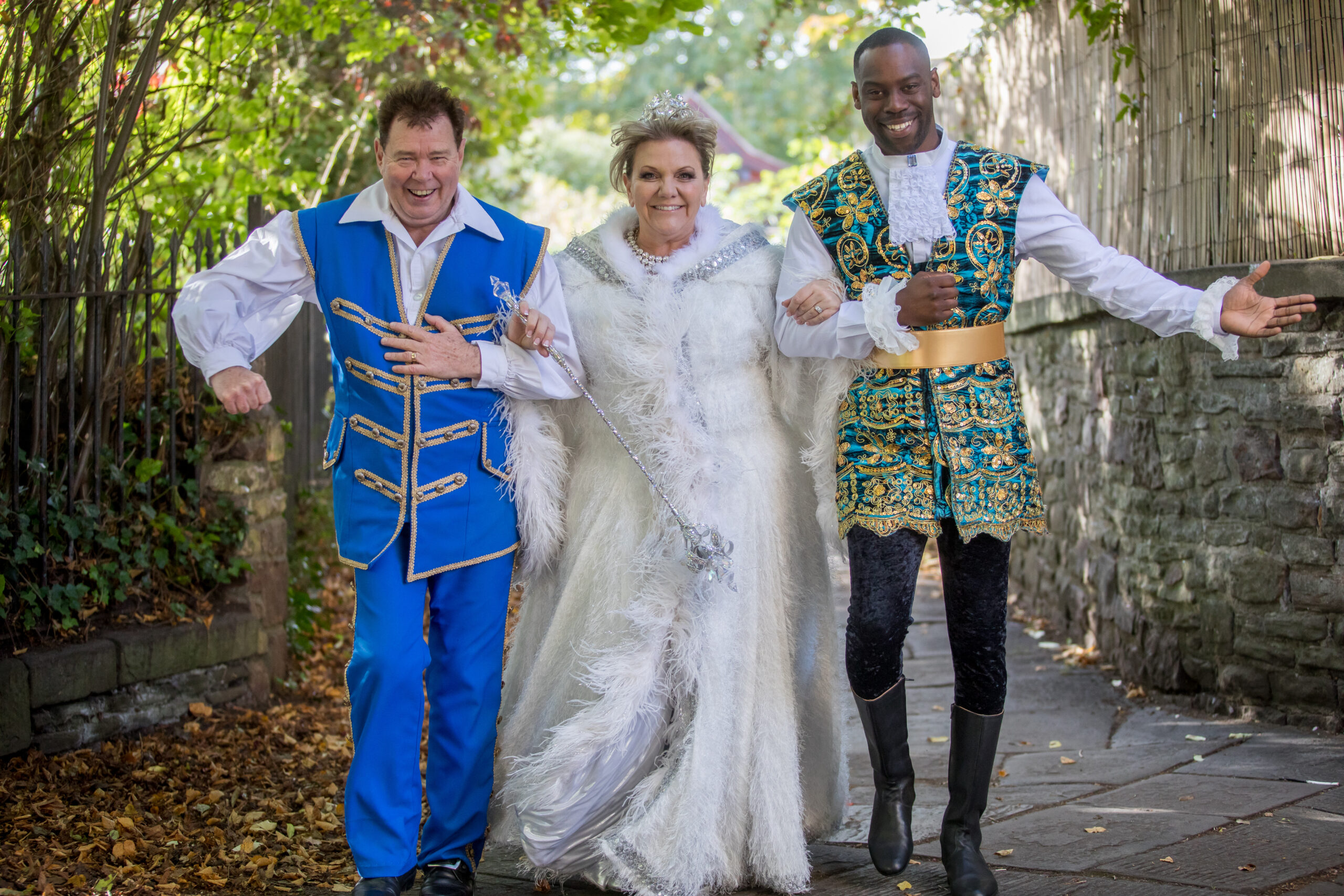 The fairy godmother walks arm in arm with the prince and Buttons