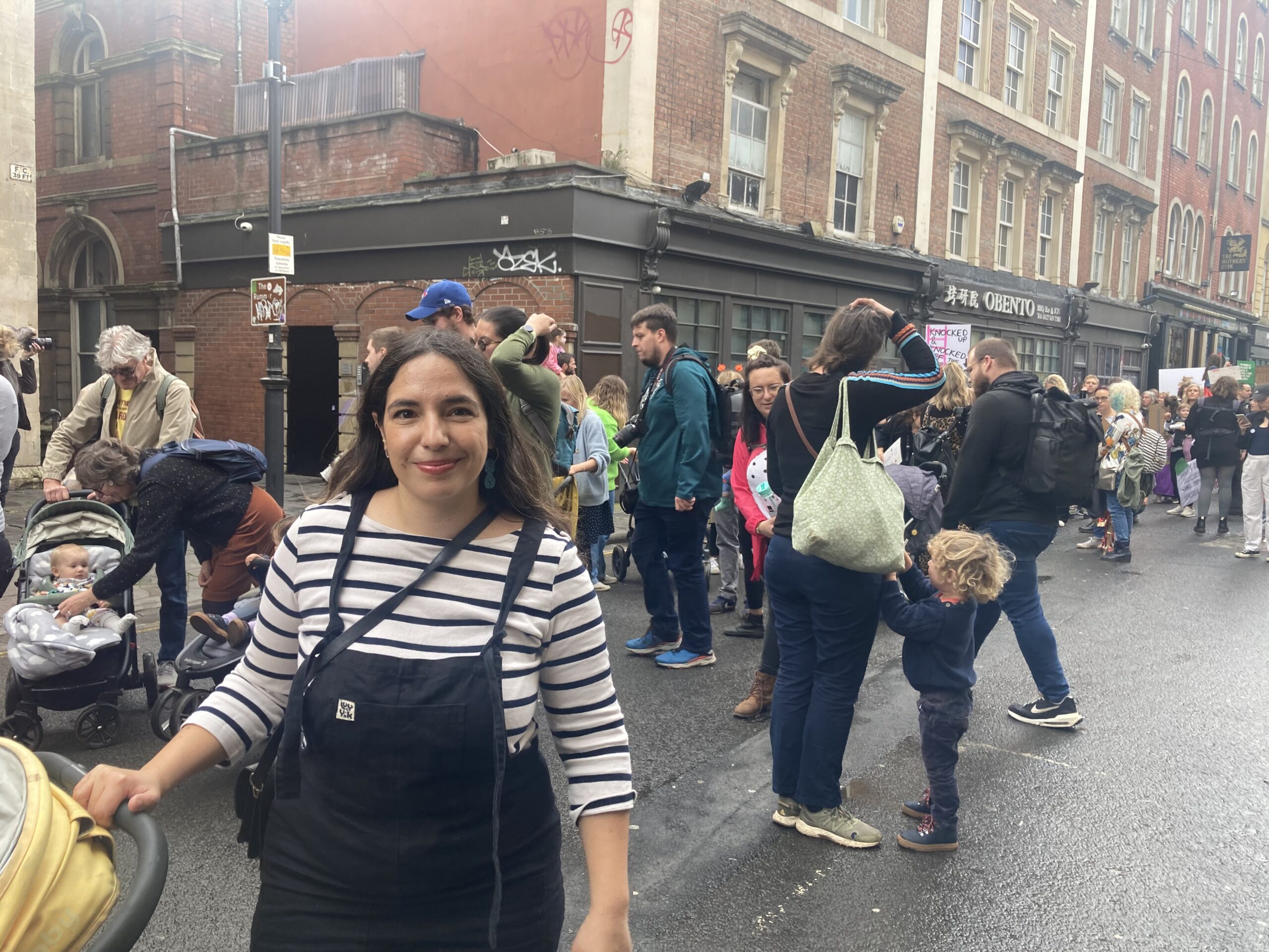 A young woman stood in the street holding a pram