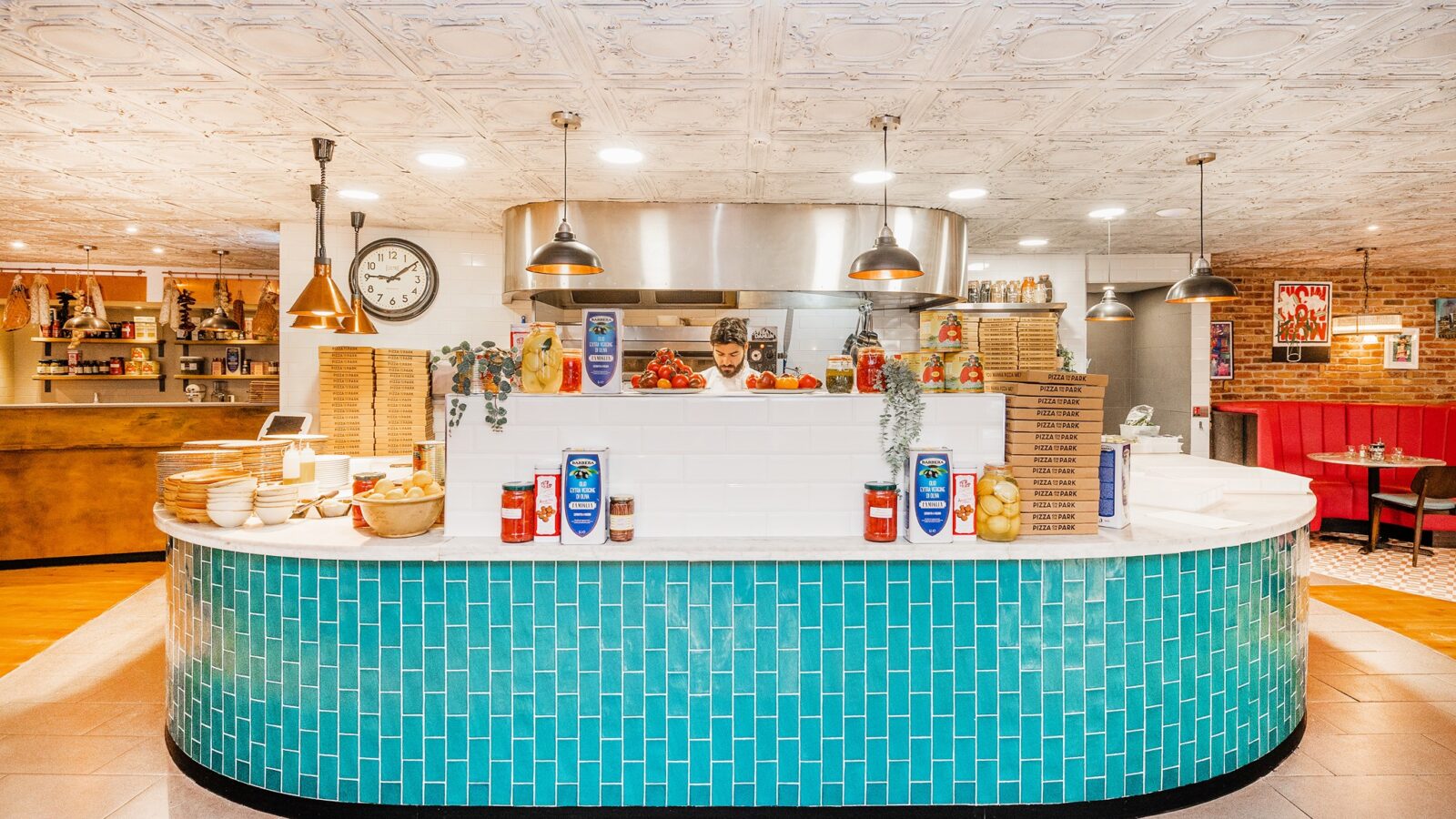 Blue and white brightly lit kitchen counter at Pizza on the Park with a chef stood behind it