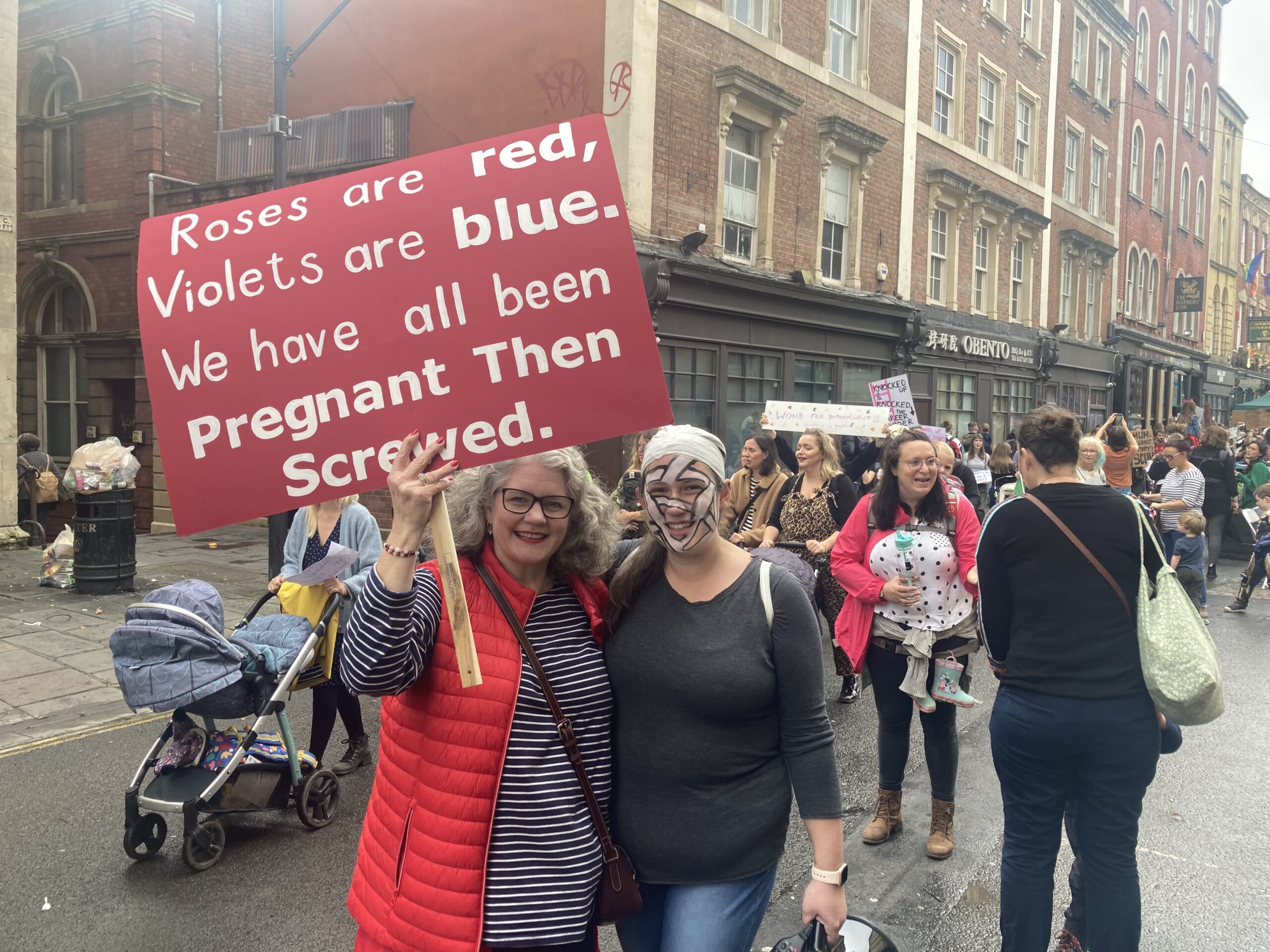 a mum and daughter stood side by side at a protest in the city centre