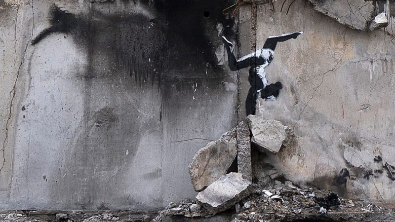 A stencil of a gymnast doing a handstand on the side of a concrete wall