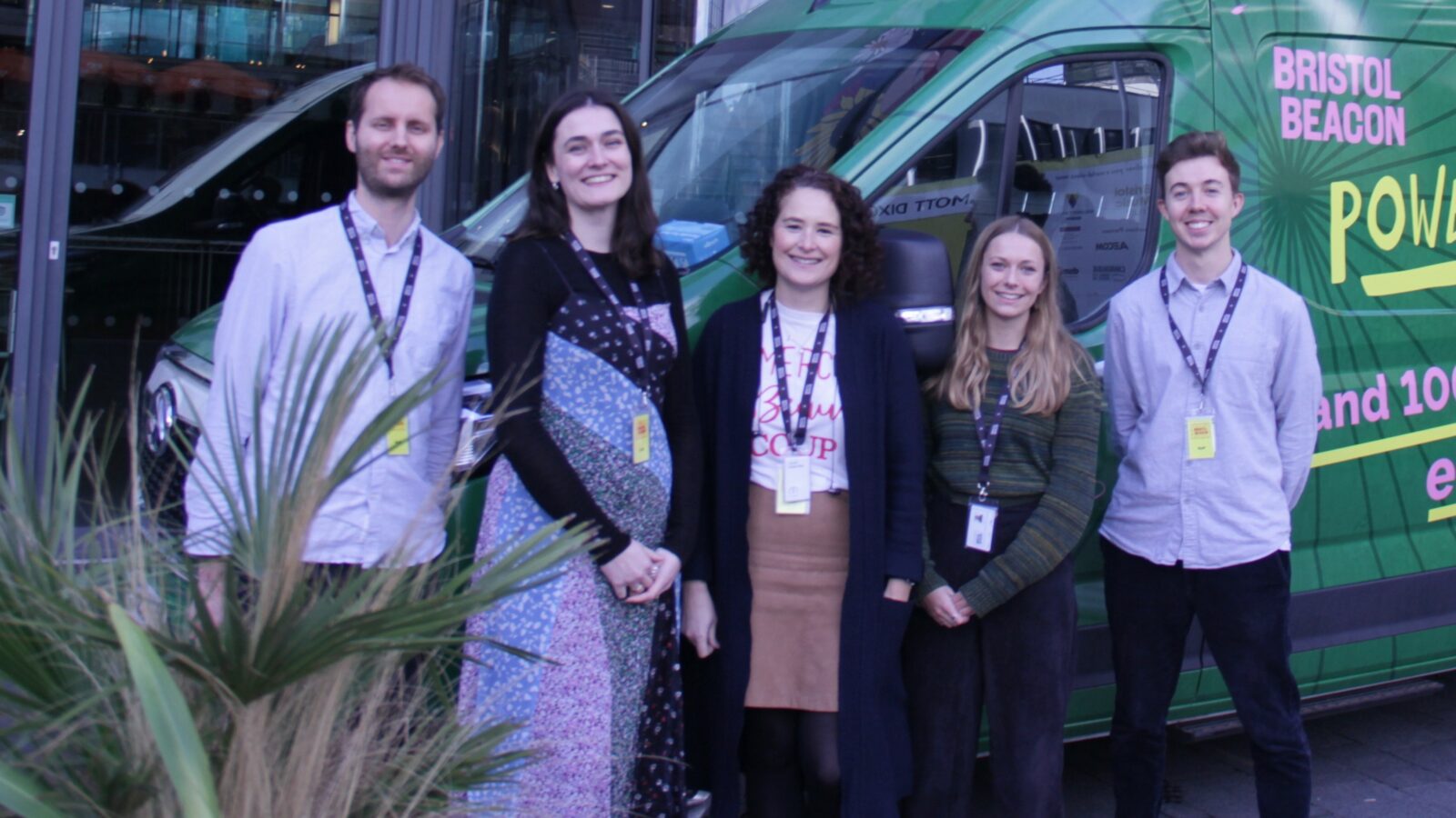 Five Bristol Beacon staff stand in front of the foyer and a green van in Bristol Beacon branding
