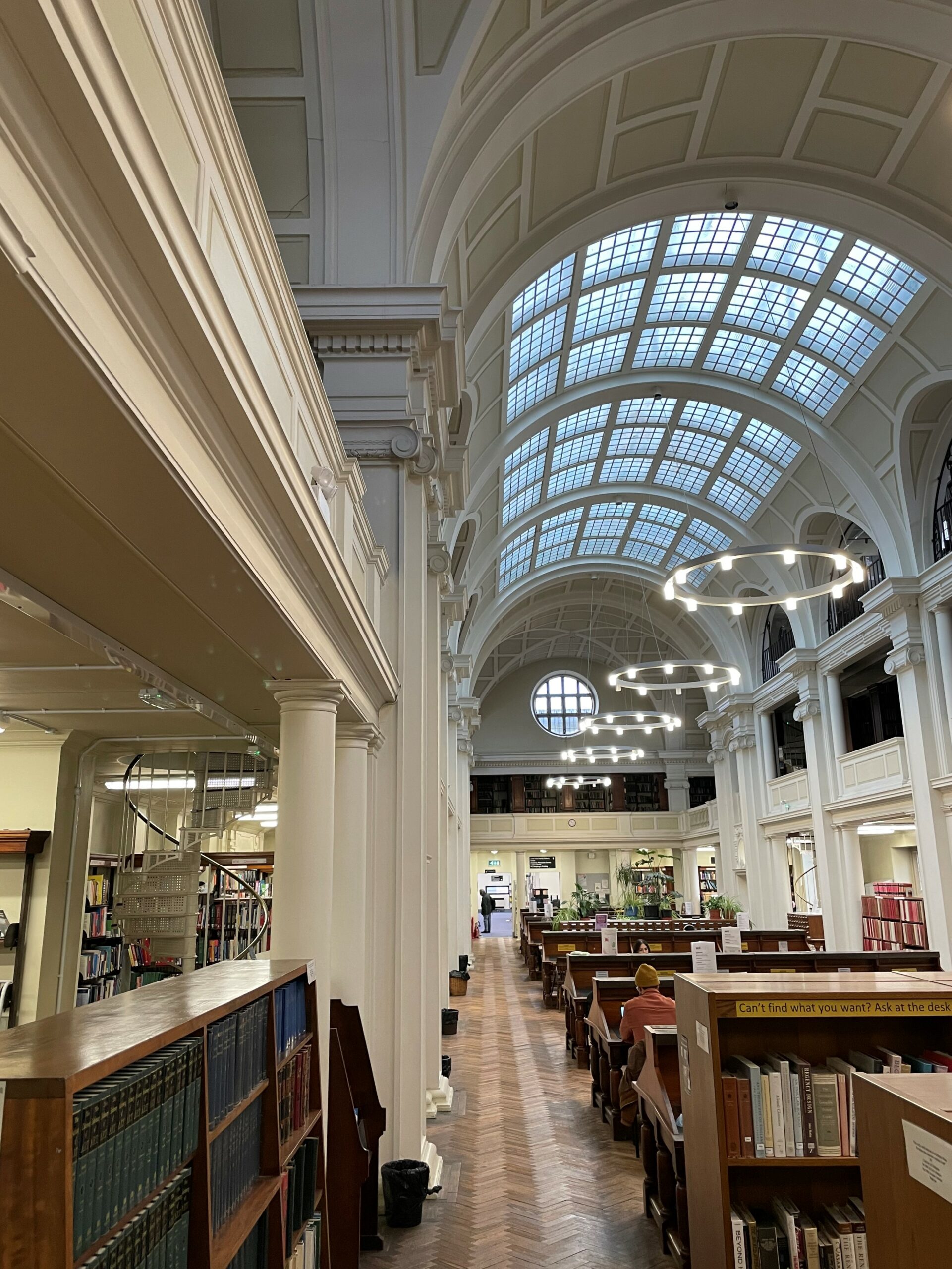 The reading room at Bristol Central Library featuring desks, a spiral staircases to the upper floors and a huge curved skylight
