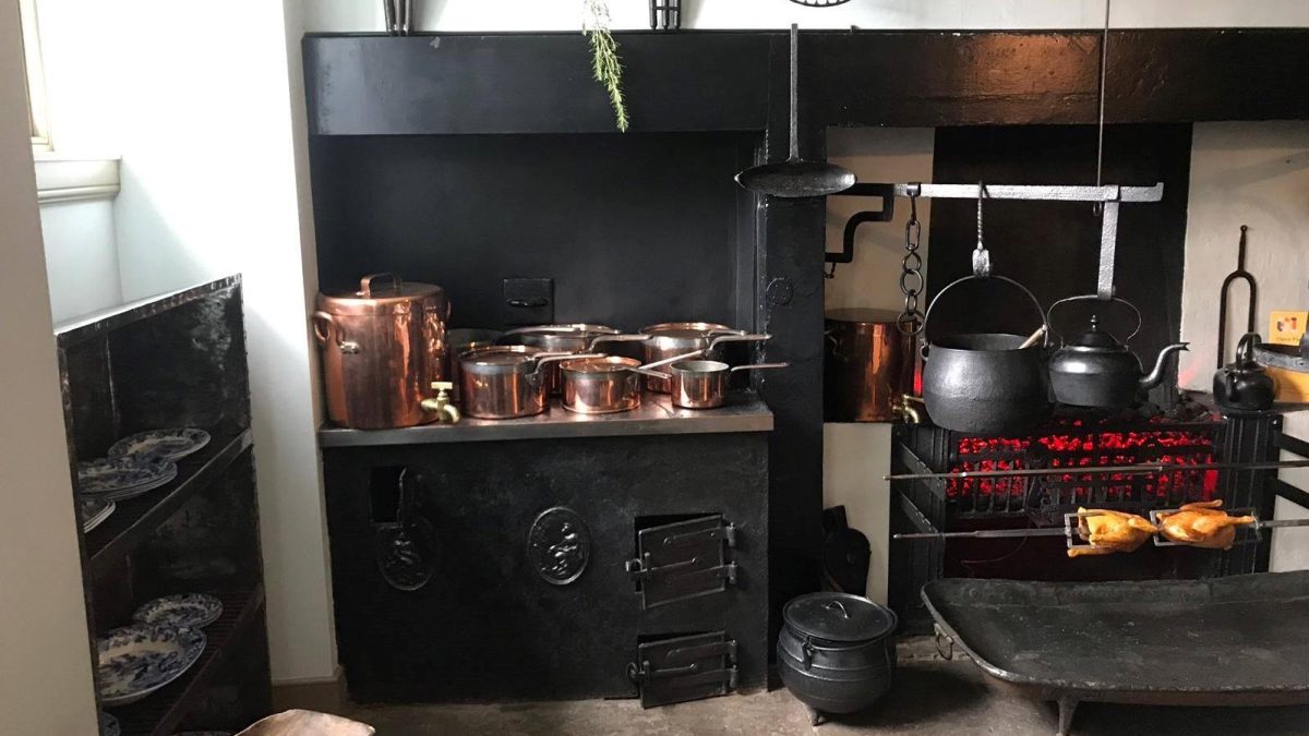 A Georgian stove, lit fire, pots and pans, and two chickens on a spit