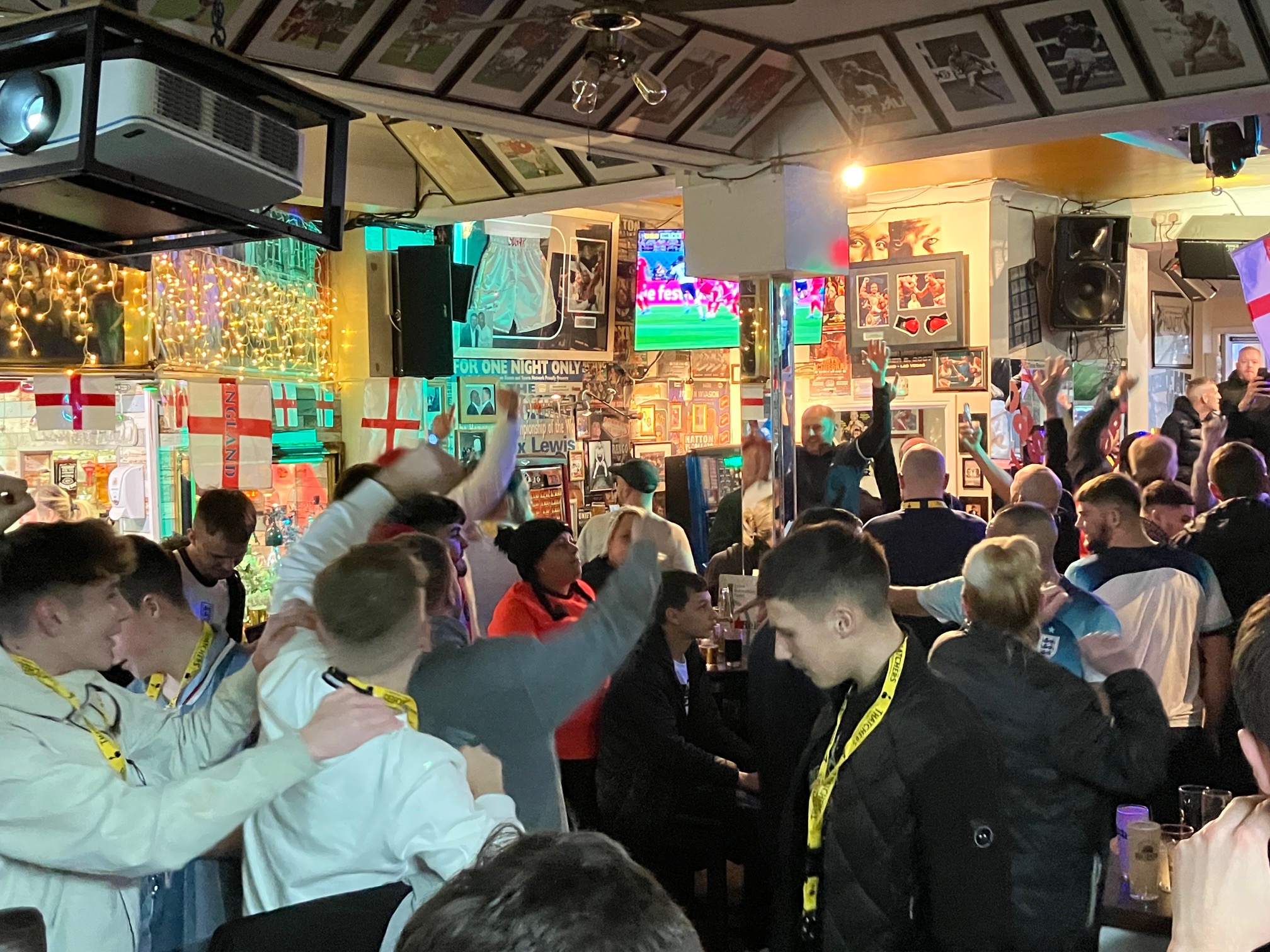 Football fans cheering on the England football team in a packed pub