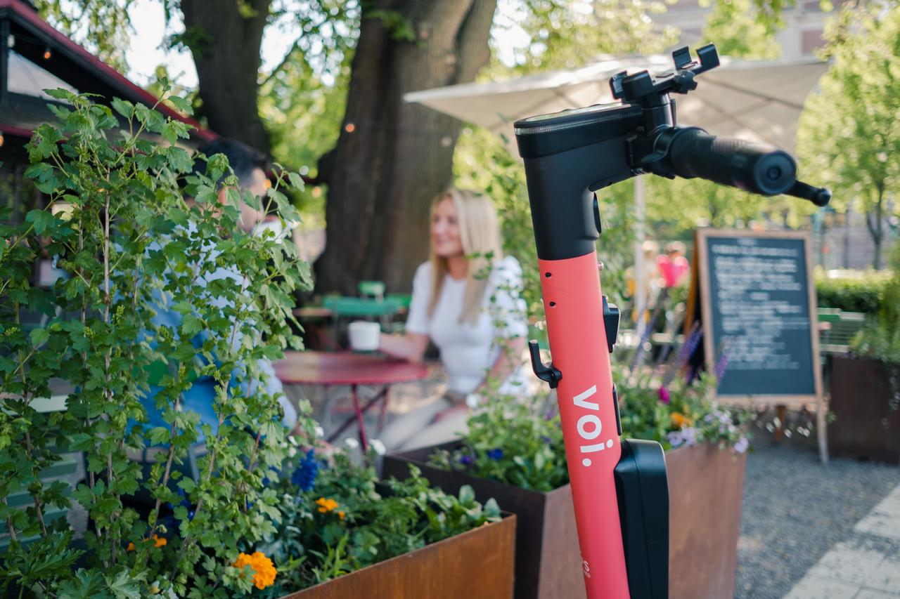 an e-scooter next to someone dining outside on a bright day