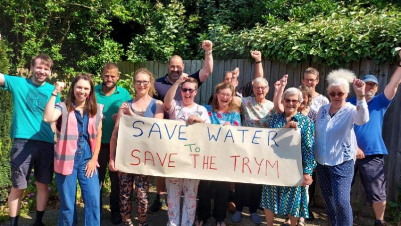 A group of people hold a banner with 'Save Water - Save the Trym' written on it