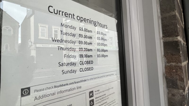 A sign in a window giving the opening times of Lloyds bank