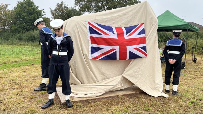 A covered statue flanked by three sea cadets in uniform