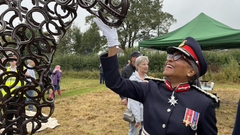 A lady in uniform admires a horse statue