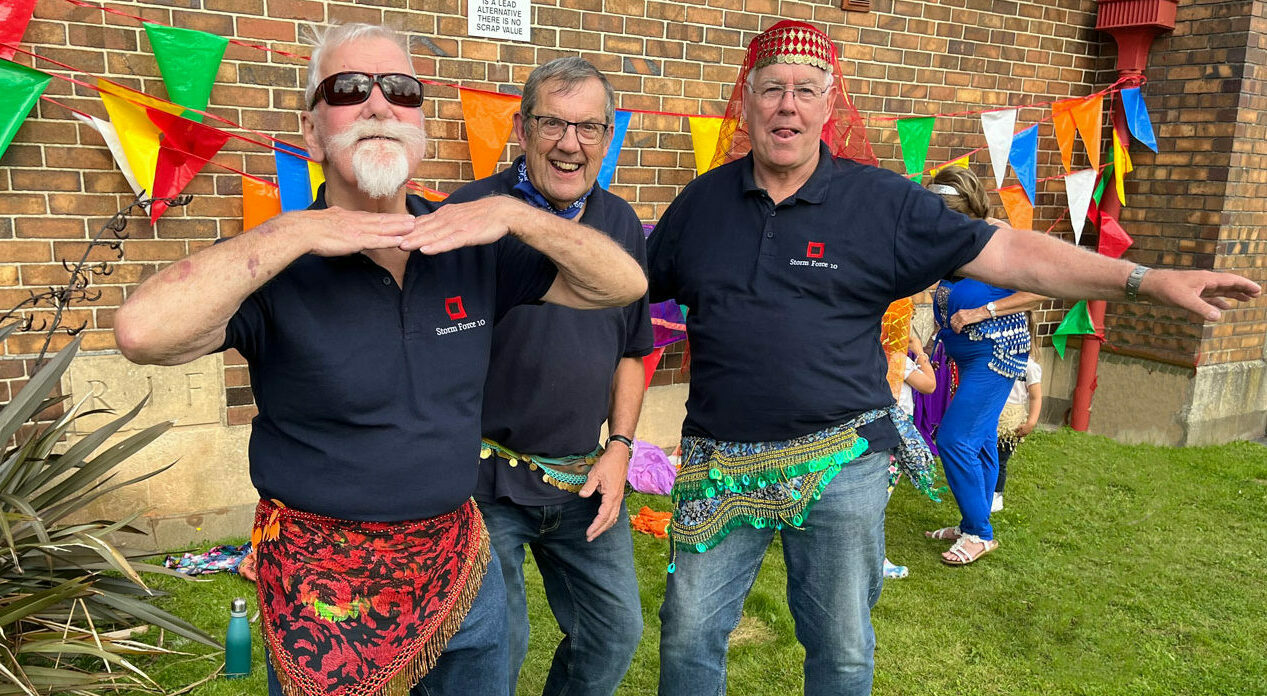 Three sea shanty singers wearing belly dancing belts