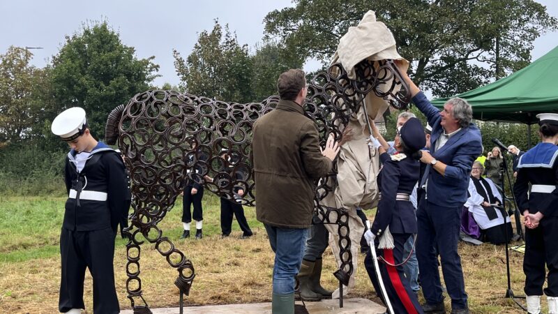 A statue of a horse has a cover pulled from it