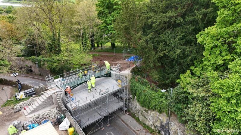 A bridge seen from above with a safety platform below. It's being worked on by men in hi-vis