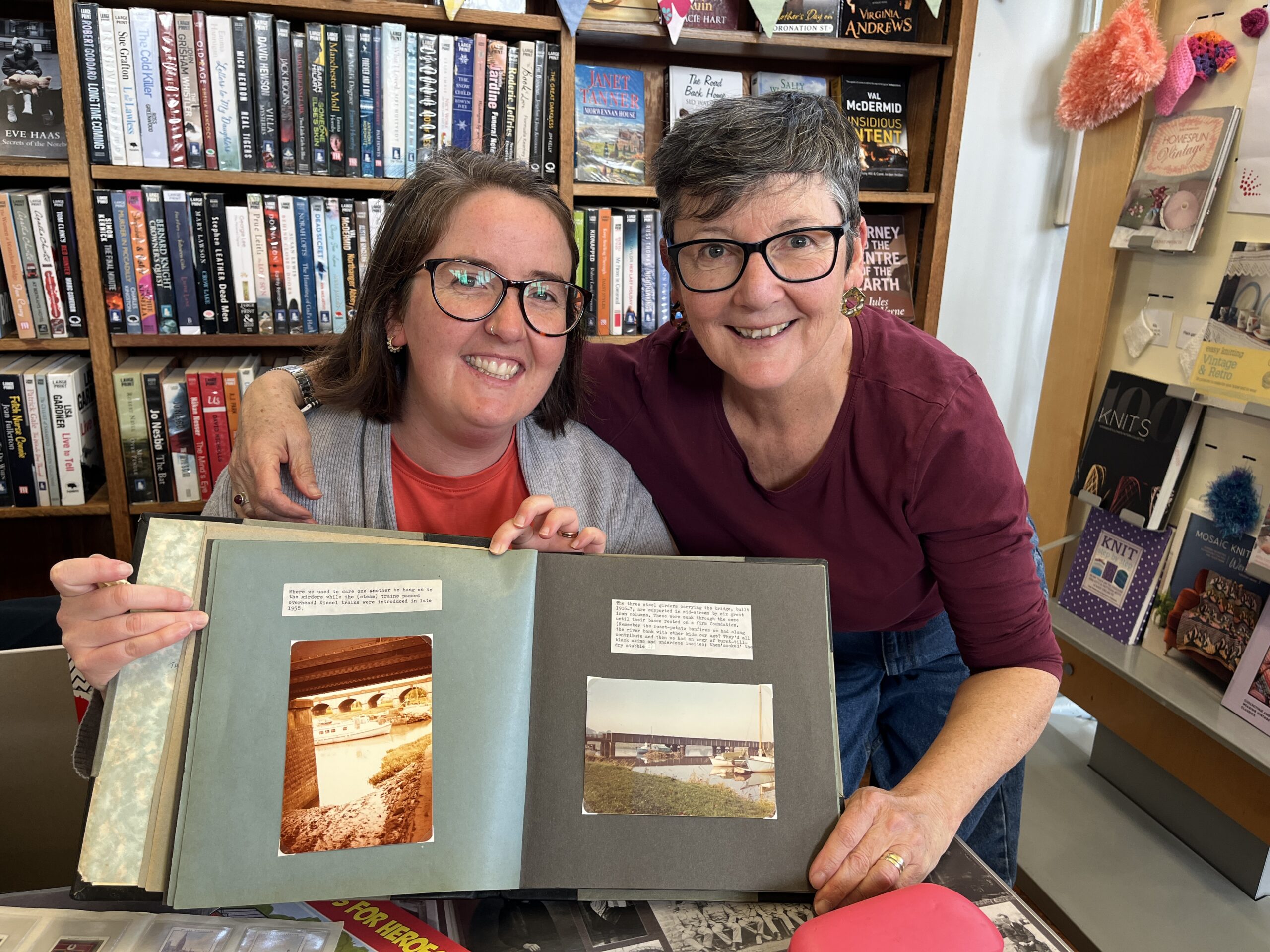 Two smiling women proudly show a photo album