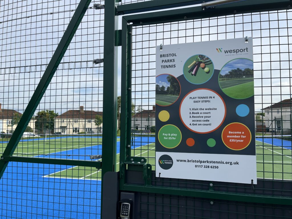 A gate into a tennis court and a poster showing information about how to book