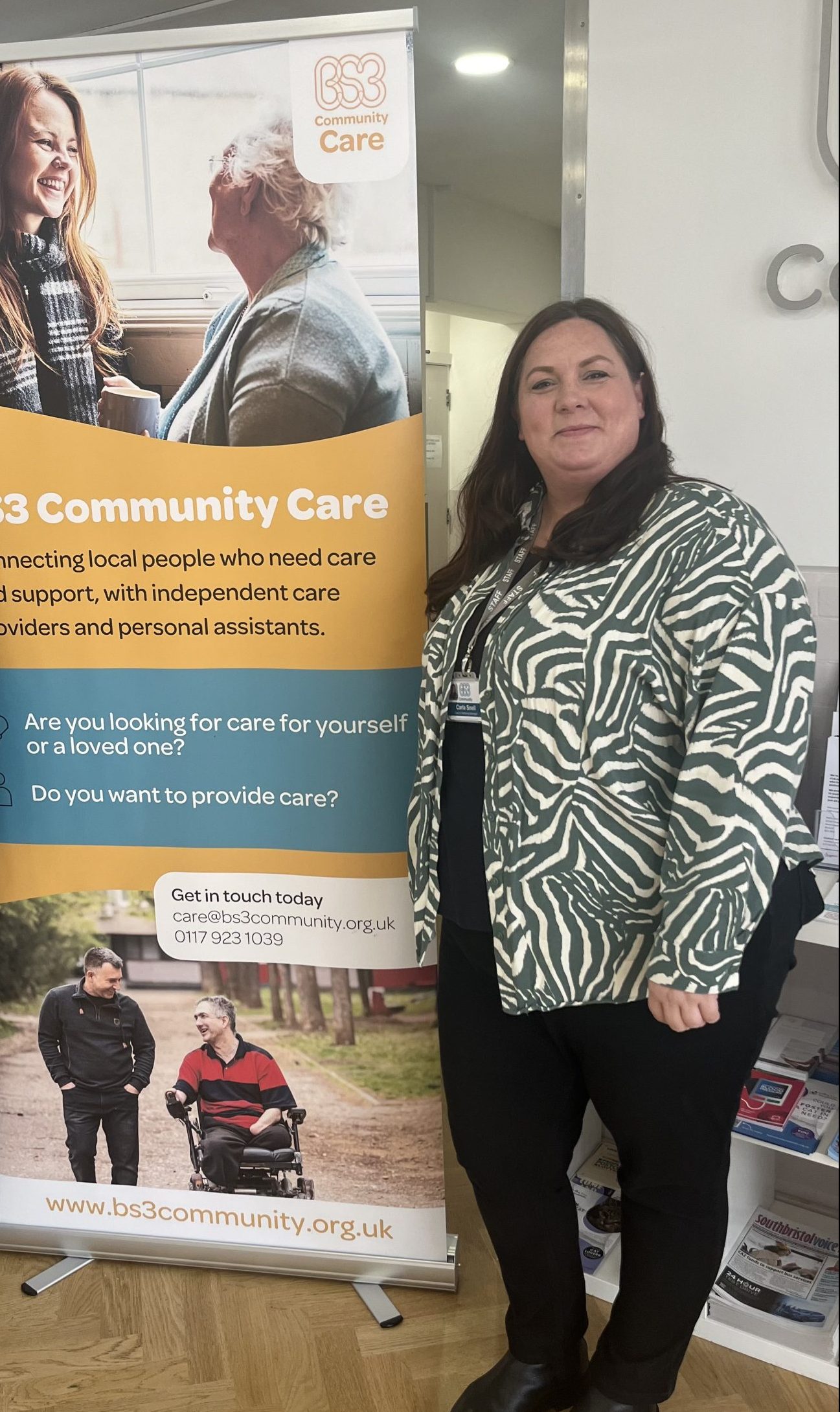Carla stands next to a banner which explains BS3 community care