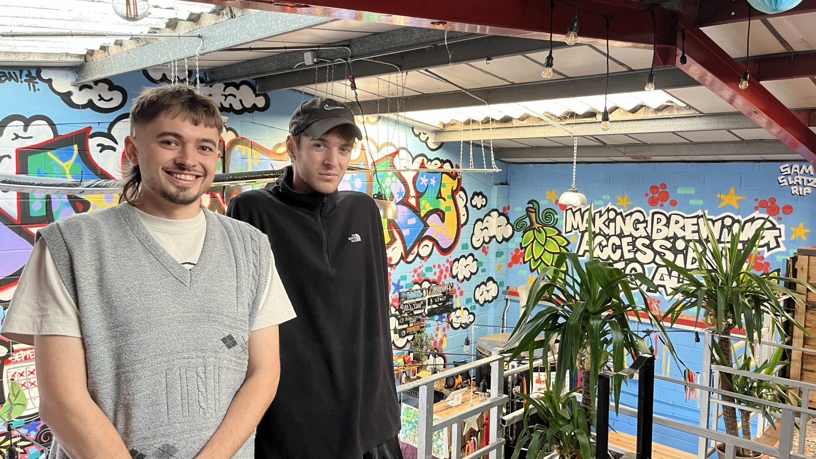 Two brewery owners stand on a mezzanine overlooking the bar area