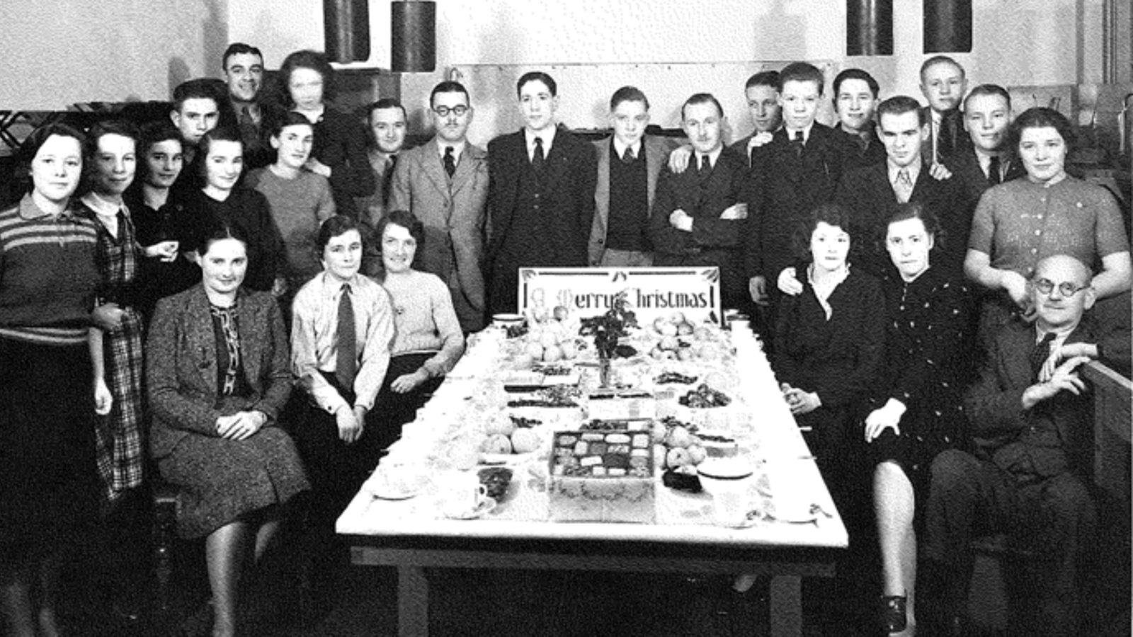 A black and white photo showing a group of men and women around a table at the BAC factory