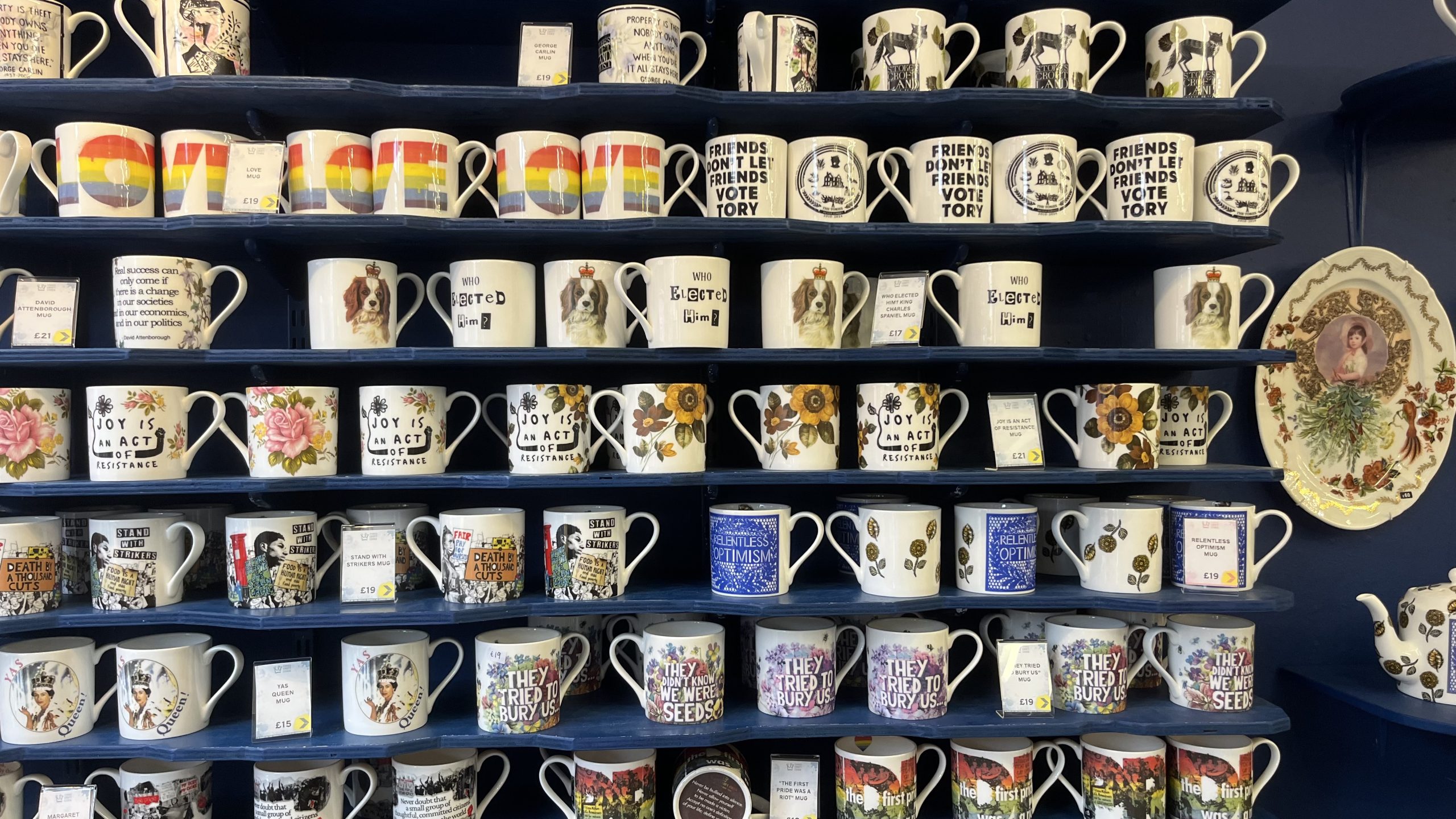A display shelf is piled high with artistic mugs 