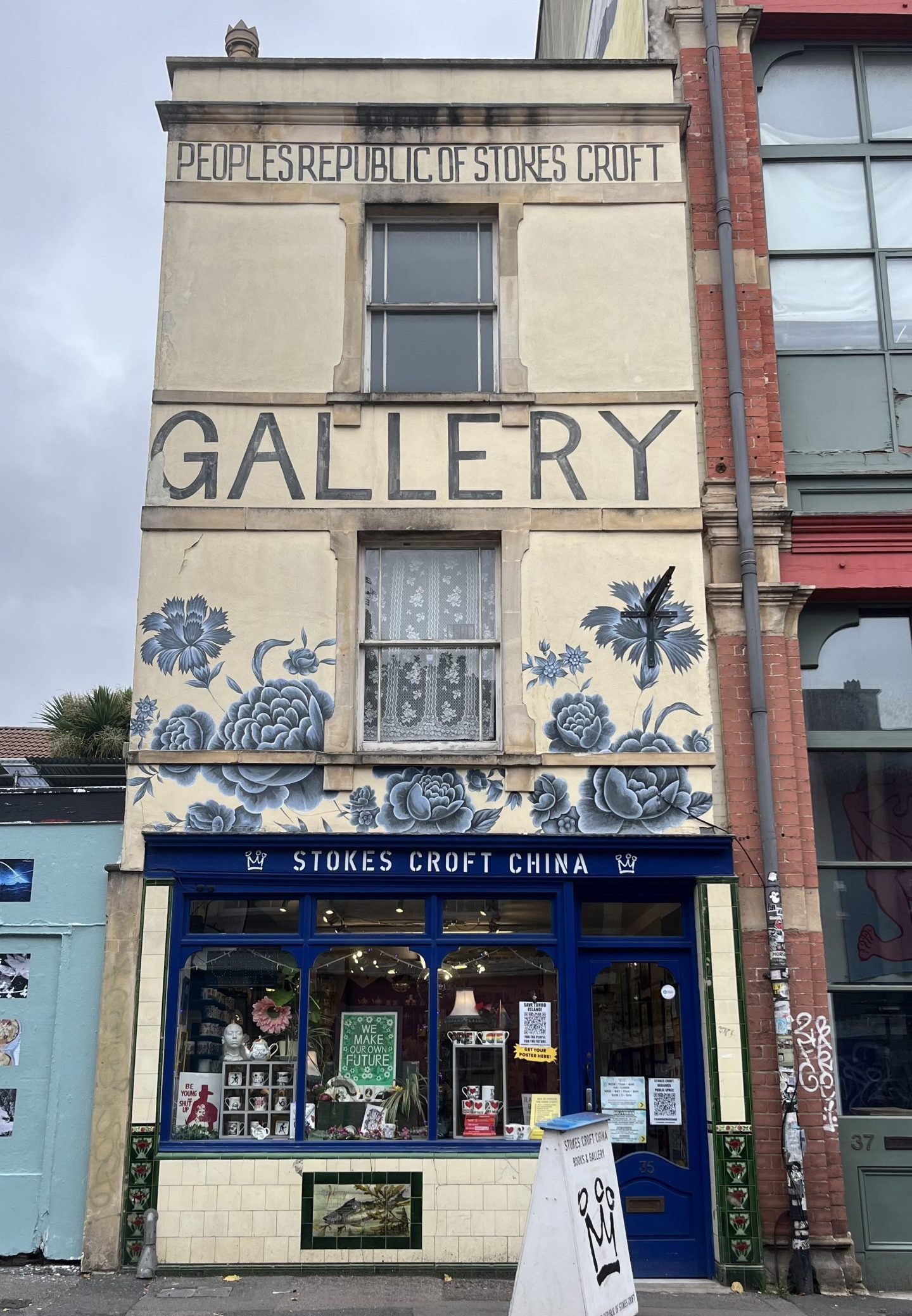 A narrow townhouse has been converted into a china shop that has a mural on the front facade of it 