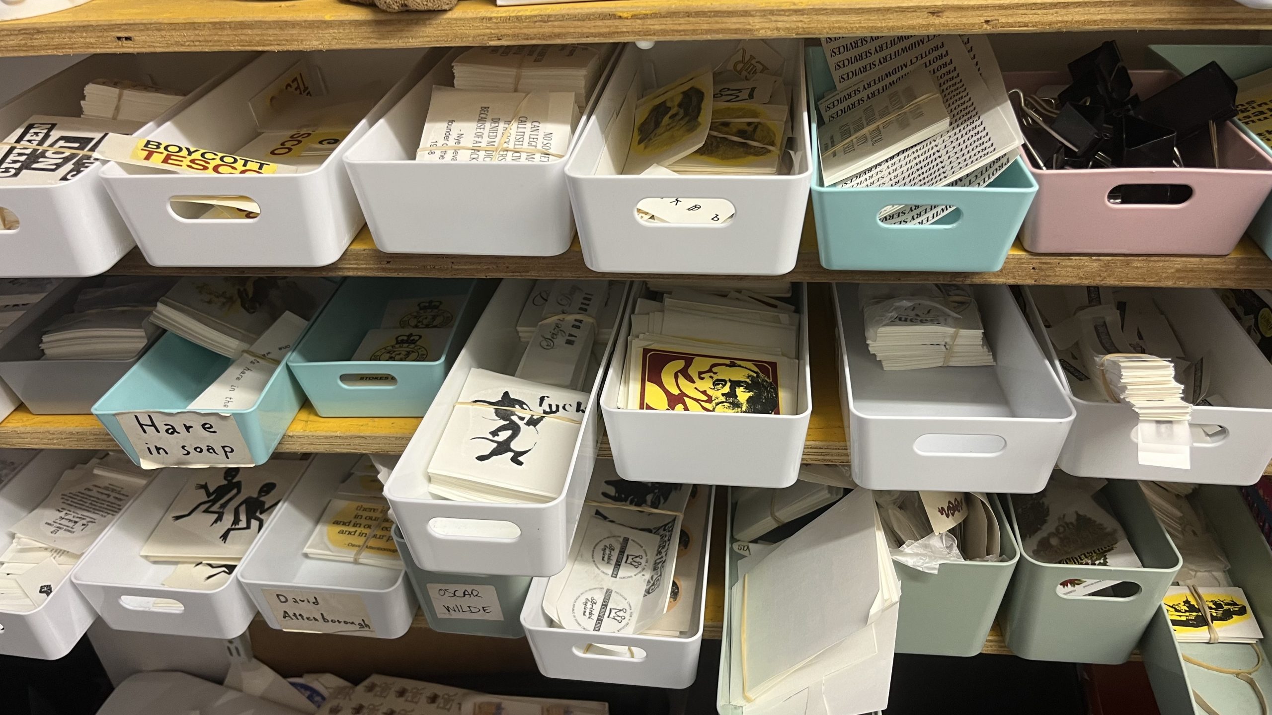 Boxes containing transfer prints are haphazardly stacked on shelves