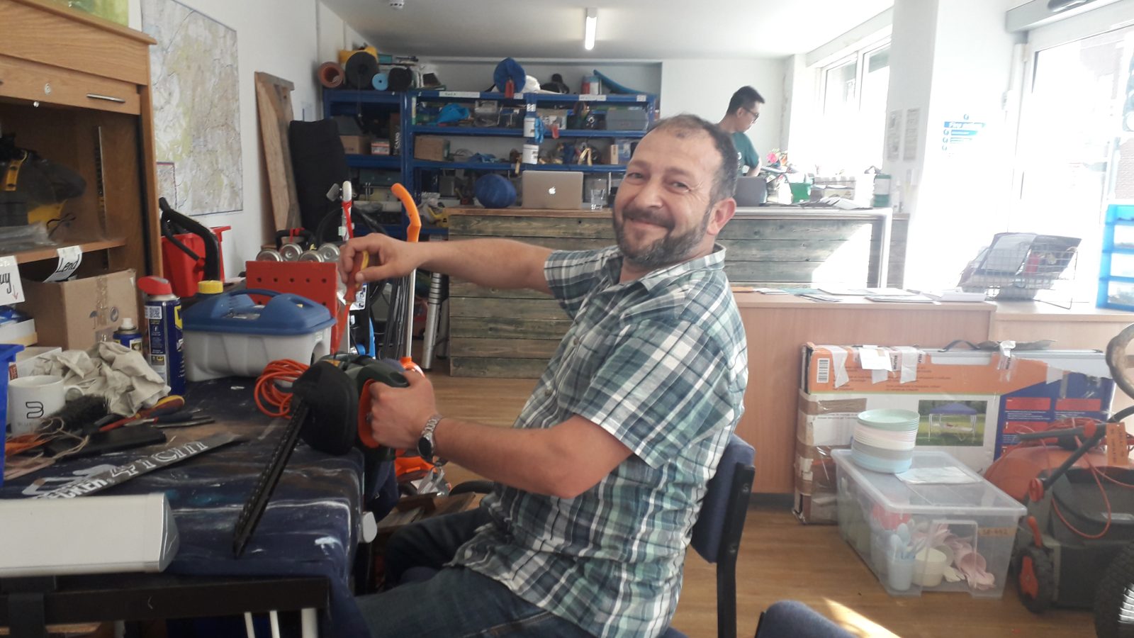 A man repairs a hedge strimmer at a library of things