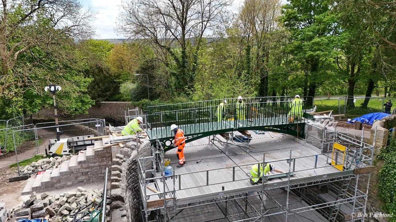Aerial view of a small footbridge with a working platform underneath it with people working