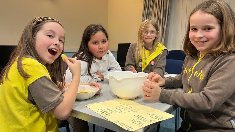 Four girls at a table with two bowls which contain fruit