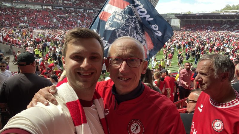 Two male Bristol City fans smiling at Ashton Gate after they secured a playoff spot.