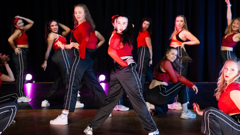 A group of dancers in red tops and black sweatpants