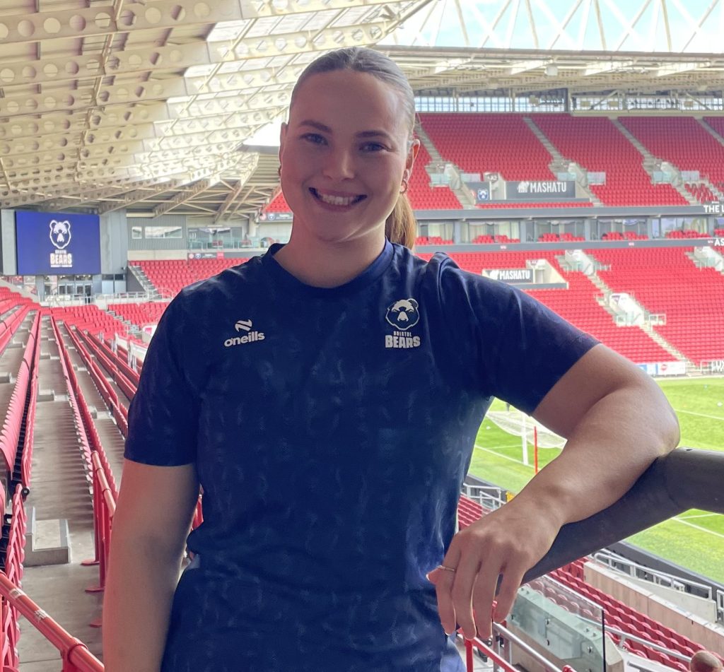 Holly Phillips in the stands at Ashton Gate Stadium. Holly is facing the camera and smiling.