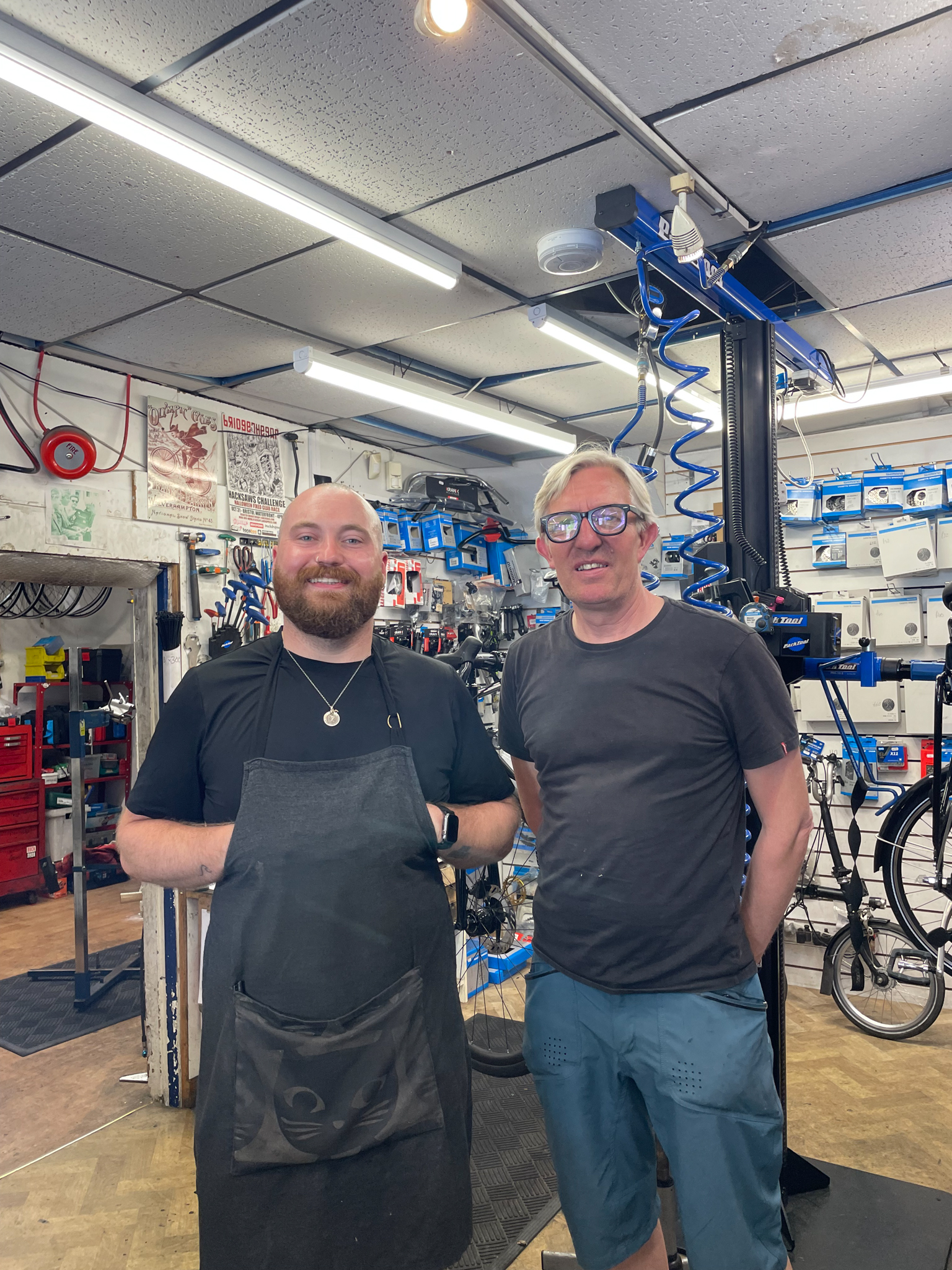 Two men stand in a bicycle repair shop