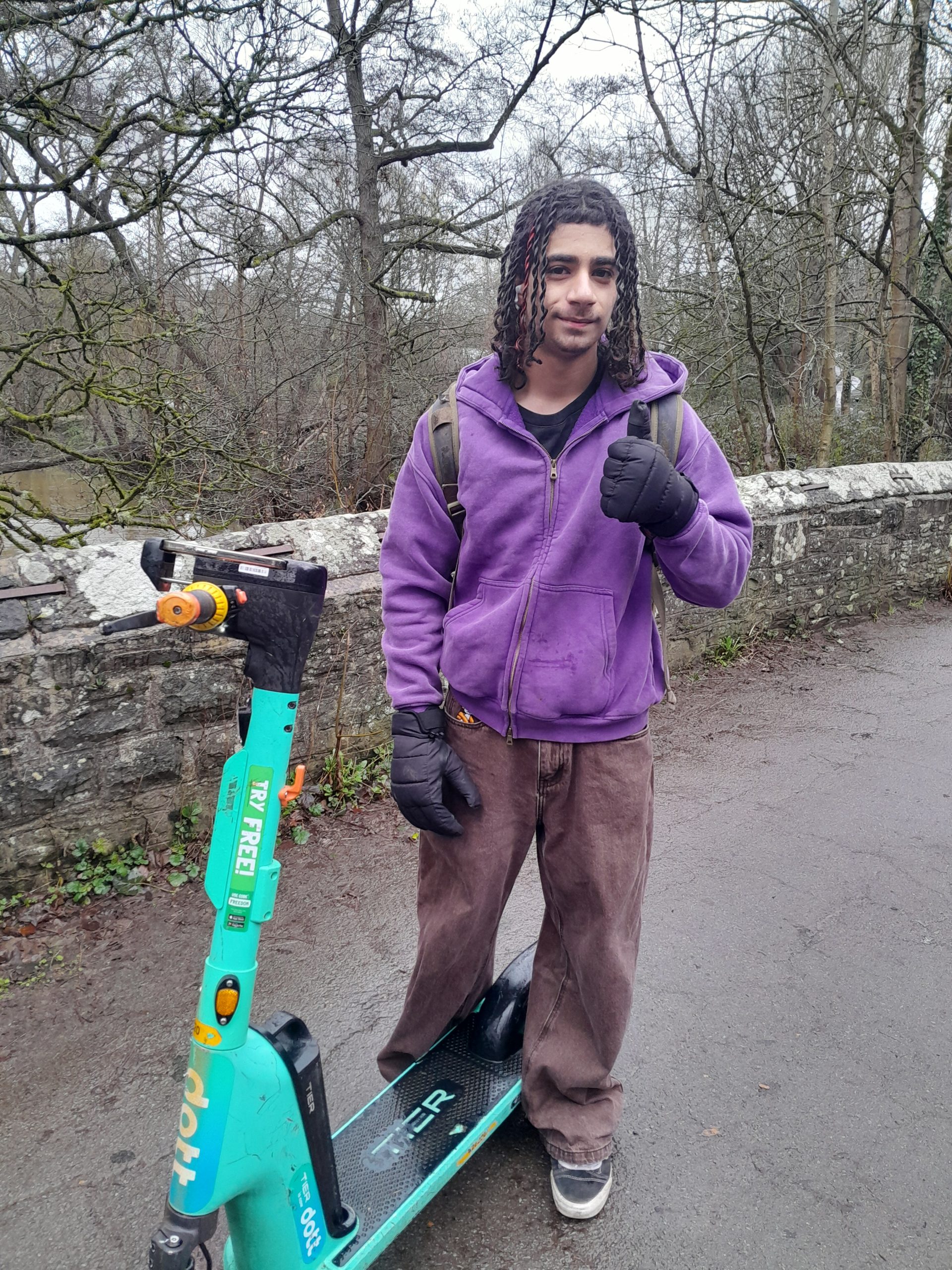 A young man on his scooter giving a thumbs up sign